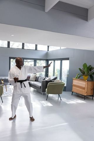 African american senior practicing karate in sunlit minimalist midcentury living room