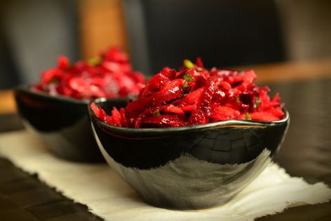 Vibrant shredded beetroot salad in black ceramic bowls, garnishing healthy vegan side dish, close-up