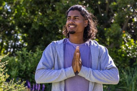 African american man practicing gratitude meditation outdoors in sunlit garden