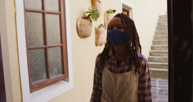 Female Florist Wearing Apron and Mask Standing by Doorway - Download Free Stock Images Pikwizard.com