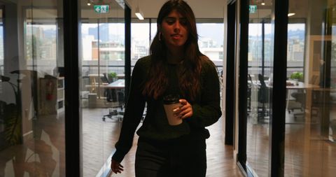 Confident Businesswoman with Coffee in Modern Workspace