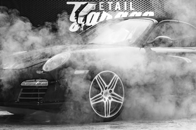 Luxury car surrounded by smoke at an auto detailing garage. Can be used for automotive service advertisements, car detailing promotions, luxury vehicle branding, and automotive industry articles.