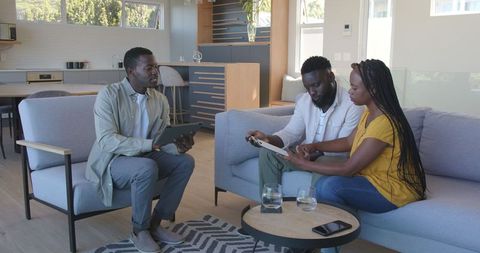 Couple consulting financial advisor at home with digital devices