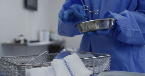 Surgical technician preparing sterile instruments with kidney dish, forceps and gauze