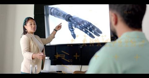 Businesswoman presenting robotic prosthetic hand on screen at technology meeting