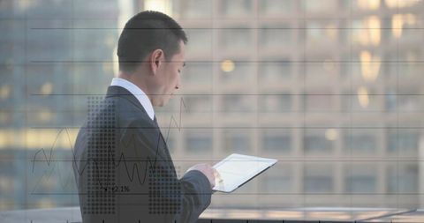 Asian executive analyzing tablet data with urban skyline overlay, corporate analytics