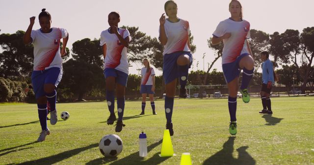 Female soccer team is practicing drills outdoors on a bright sunny day. The image showcases four athletes in action, performing practice routines with focus and intensity. Ideal for use in sports blogs, coaching websites, fitness and training content, ads encouraging female participation in sports, and promotional materials for soccer clubs and events.