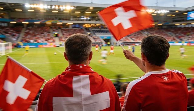 Cheering swiss football fans waving swiss flags in crowded stadium during match, red jerseys
