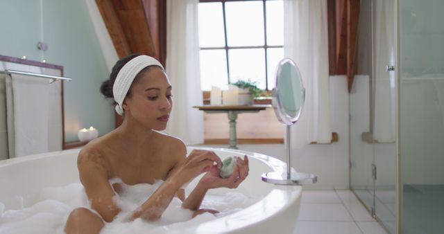 Biracial woman taking a bath applying beauty face mask - Download Free Stock Photos Pikwizard.com