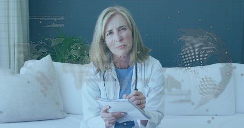 Female physician conducting telehealth consultation on sofa with global data overlay