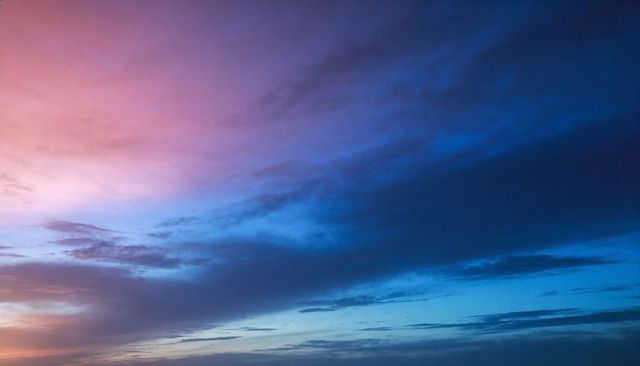 Pastel twilight sky showing pink and blue cloud bands over minimalist open horizon at dusk