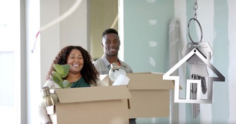 Couple Carrying Boxes into New Home with Real Estate Key Symbol