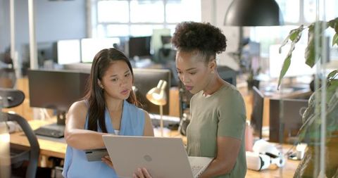 Businesswomen collaborating on project in modern office environment