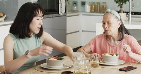 Asian mother and daughter sharing meal in contemporary kitchen