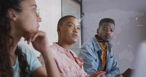 Shaved-head woman leading diverse team brainstorming with laptop and global map overlay