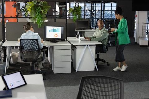 African american coworkers collaborating in modern office with analytics dashboard and plants