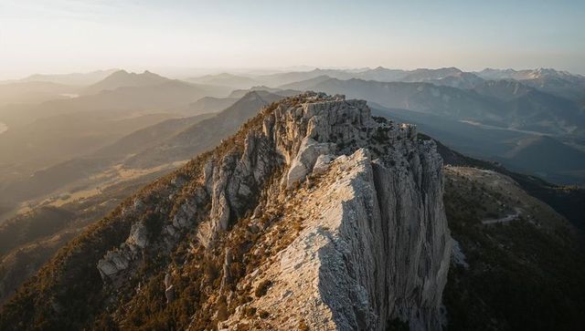 Jagged limestone ridge stretching toward sunlit horizon over remote high-country panorama