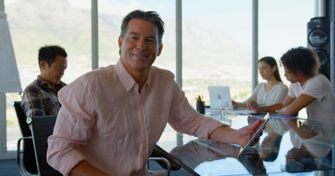 Smiling business executive holding tablet in modern conference room