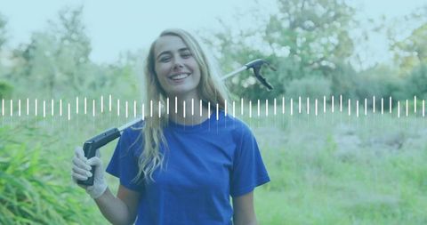 Smiling volunteer holding trash picker in lush park setting