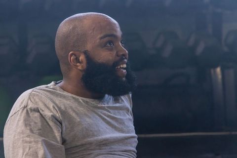 African american man looking up in dim gym lowkey beard sweating for fitness inspiration