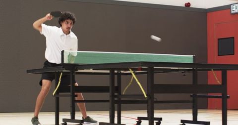Dynamic Man Playing Table Tennis in Sports Hall