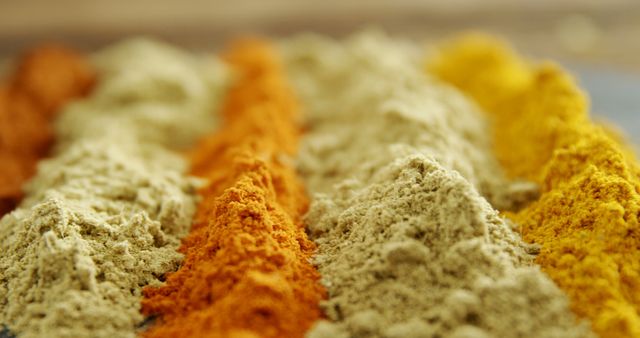 Various colorful spices are lined up in heaps, showcasing a range of flavors and culinary possibilities. Spices like these are essential in cooking, adding depth and complexity to dishes around the world.