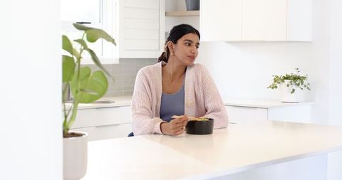 Woman Enjoying Breakfast in Minimalist Kitchen Setting