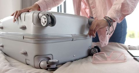Young woman packing suitcase with travel essentials