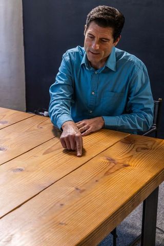 Middle-aged professional pointing at wooden table in office setting