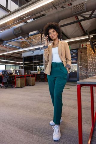 Confident businesswoman conversing on smartphone in modern open office