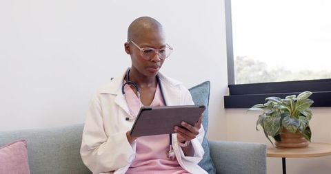 African female clinician reviewing patient records on tablet in bright clinic waiting room