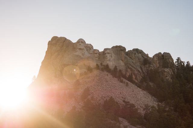 Sunlight breaking over Mount Rushmore National Memorial with iconic presidential sculptures. Perfect for travel guides, tourism promotions, historical articles, and educational materials focusing on American landmarks.