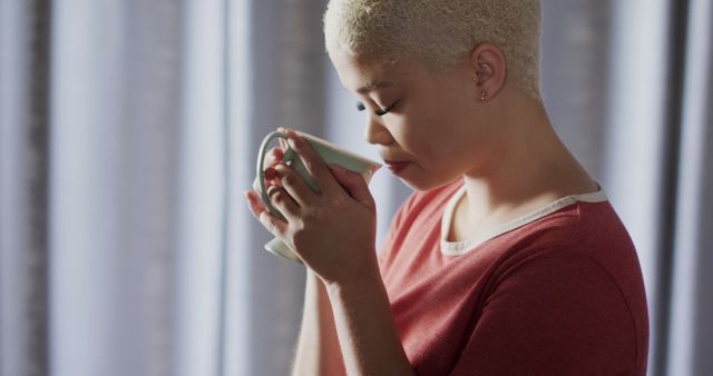 African American woman enjoying hot drink by window in soft light - Download Free Stock Images Pikwizard.com