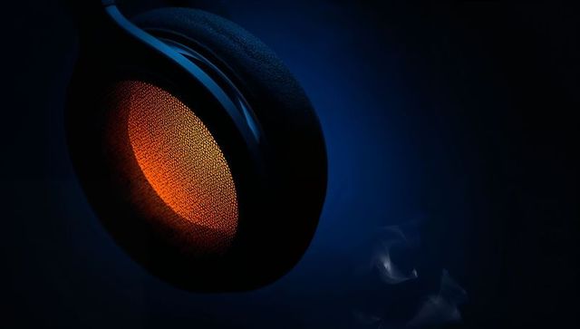 Floating over-ear headphone earcup glowing orange mesh grille with foam cushion in blue