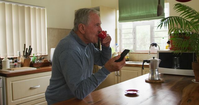 Senior Man Drinking Coffee and Using Smartphone in Kitchen - Download Free Stock Images Pikwizard.com