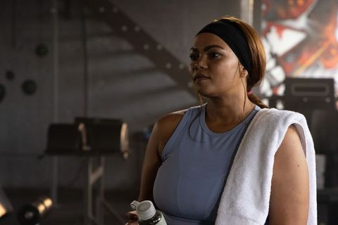 African American woman cooling down with towel and water bottle in urban gym with graffiti mural