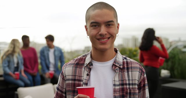 Smiling Young Man Holding Cup at Rooftop Party - Download Free Stock Images Pikwizard.com