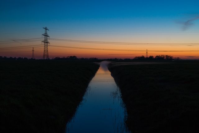 Tranquil Canal at Sunset with Electric Towers in the Background - Download Free Stock Images Pikwizard.com