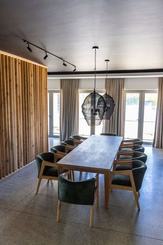 Timber dining table anchoring contemporary interior with green chairs and pendant lamps