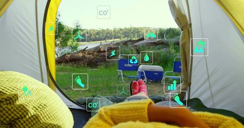 Relaxing camper viewing lakeshore from tent with augmented reality sustainability icons