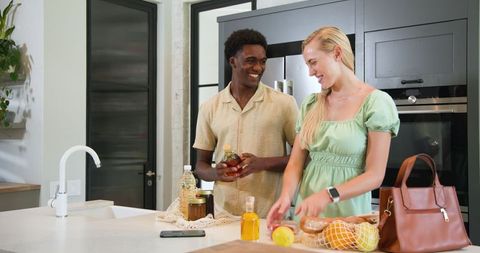 Diverse couple preparing citrus fruits in modern kitchen