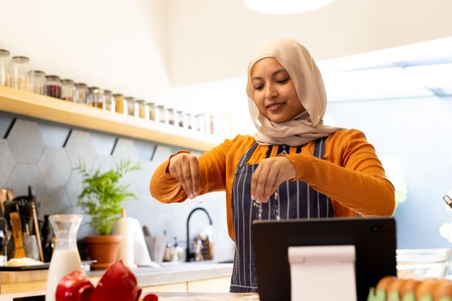 Smiling Woman in Hijab Cooking Using Tablet in Modern Kitchen - Download Free Stock Images Pikwizard.com