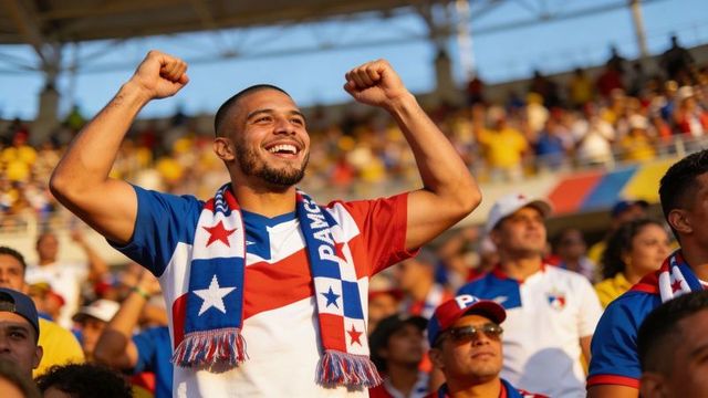 Hispanic soccer fan celebrating victory wearing panama scarf in sunny stadium crowd