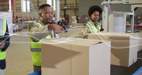 Warehouse team scanning and packing cardboard boxes on conveyor for e-commerce fulfillment