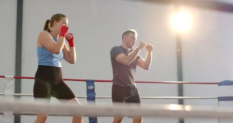 Female boxer training with coach in ring backlit sparring footwork drill