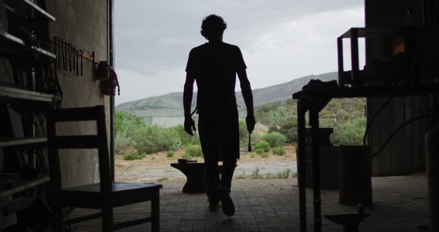 Silhouette of Man Walking Through Workshop to Outdoor Setting - Download Free Stock Images Pikwizard.com