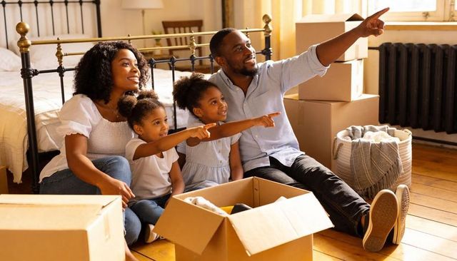 Family pointing and unpacking together in new home during move-in