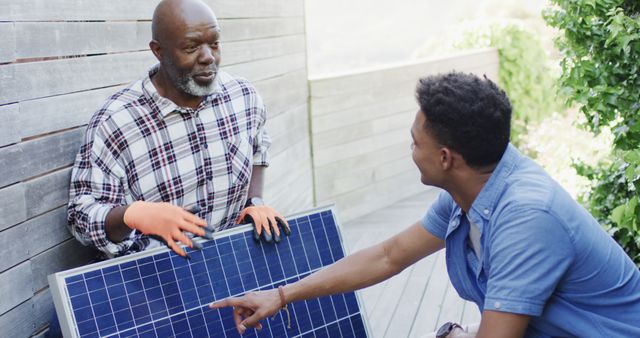 African american father showing solar panel to adult son in sunny garden - Download Free Stock Photos Pikwizard.com
