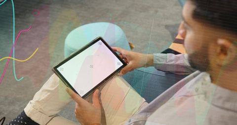 Indian man using tablet in coworking lounge for remote work and app mockup