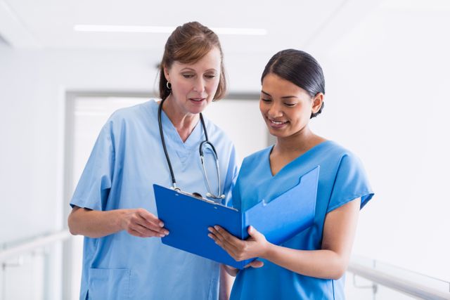Nurse and doctor discussing over clipboard in hospital corridor